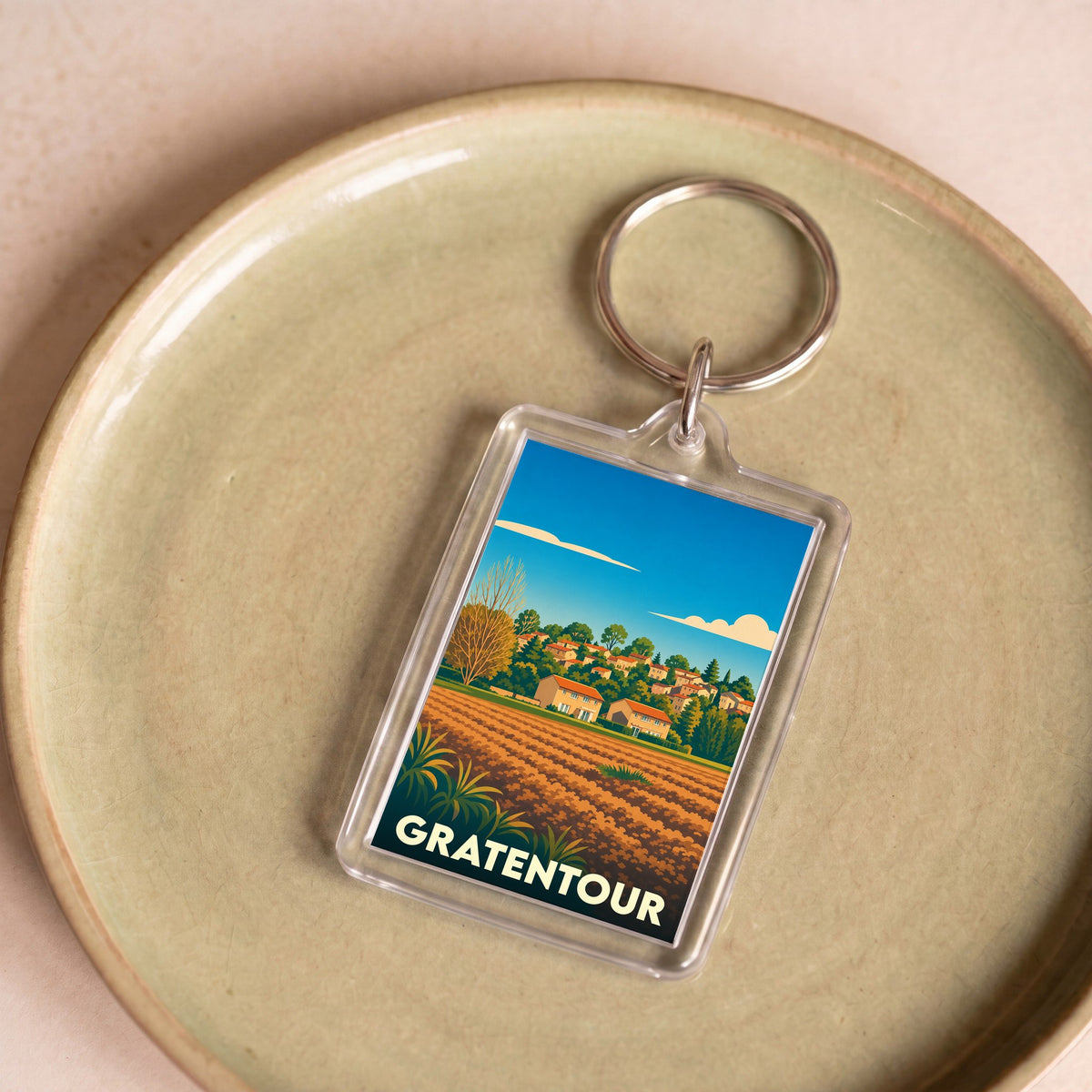Porte-clés souvenir de la ville de Gratentour avec une illustration stylisée d'un paysage champêtre.