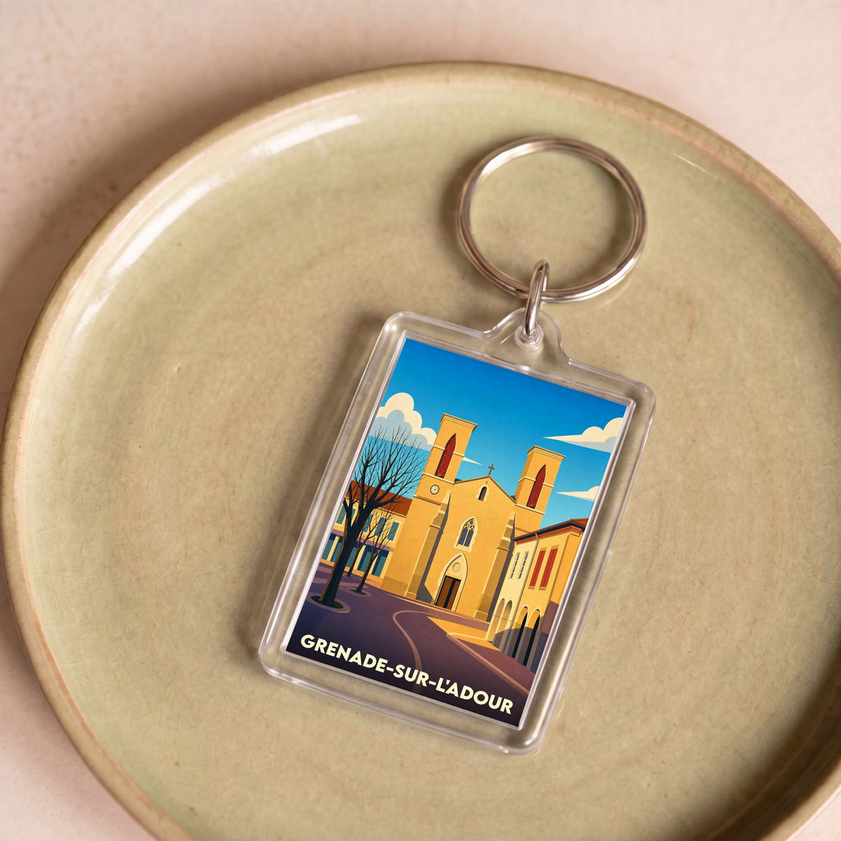 Porte-clés souvenir de la ville de Grenade-sur-l'Adour avec une illustration stylisée de son église.