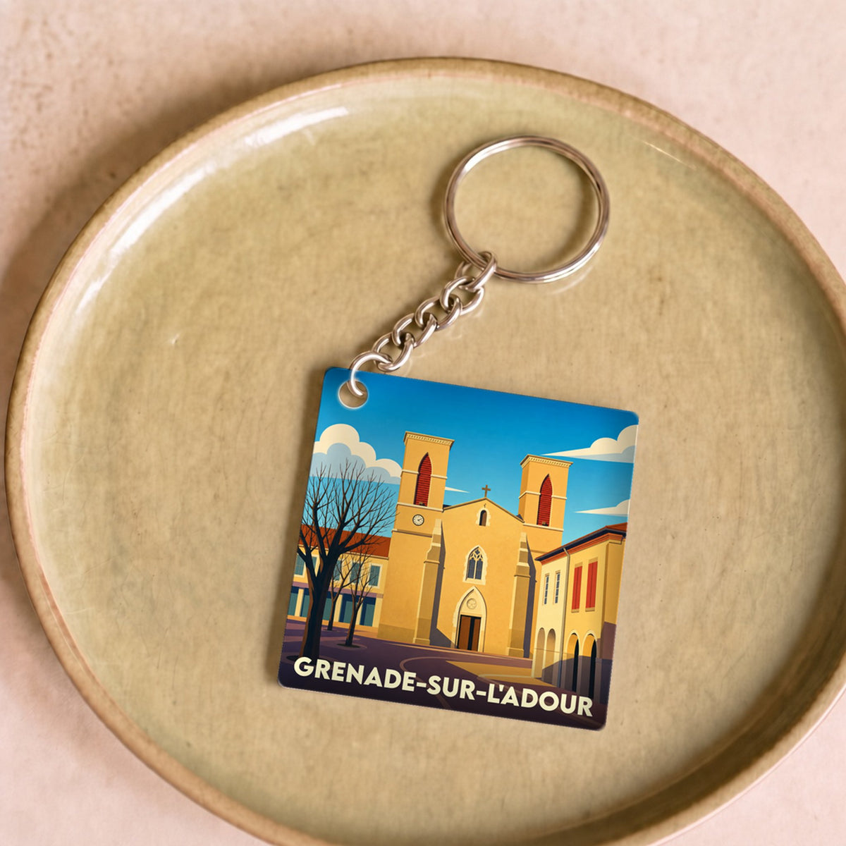 Porte-clés souvenir de la ville de Grenade-sur-l'Adour avec une illustration stylisée de son église.
