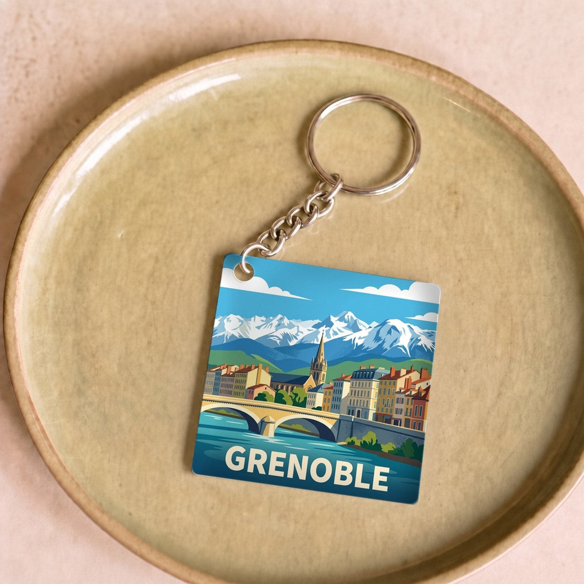 Porte-clés souvenir de la ville de Grenoble avec une illustration stylisée de son paysage urbain et montagneux.