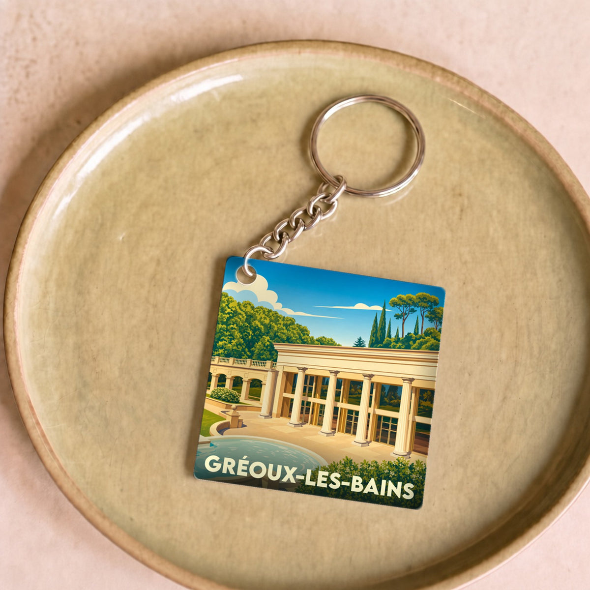 Porte-clés souvenir de la ville de Gréoux-les-Bains avec une illustration stylisée de ses thermes.