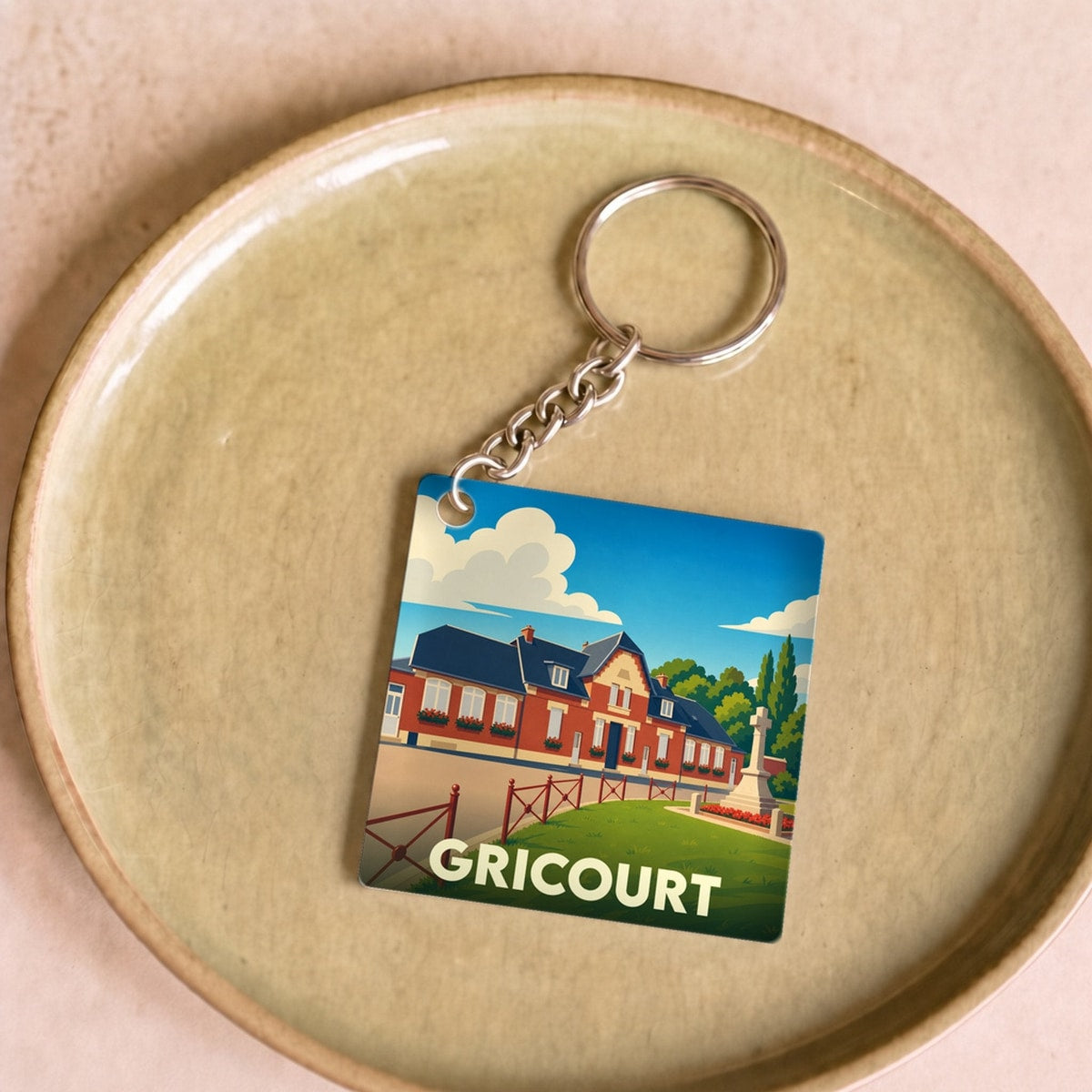 Porte-clés souvenir de la ville de Gricourt avec une illustration stylisée.