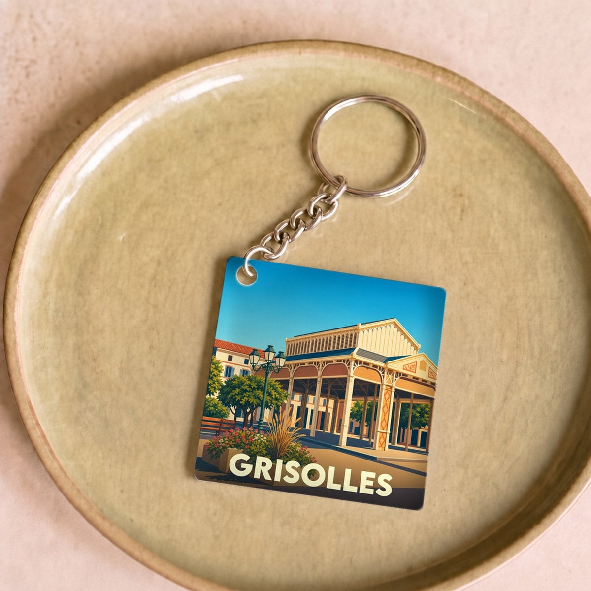 Porte-clés souvenir de la ville de Grisolles avec une illustration stylisée.