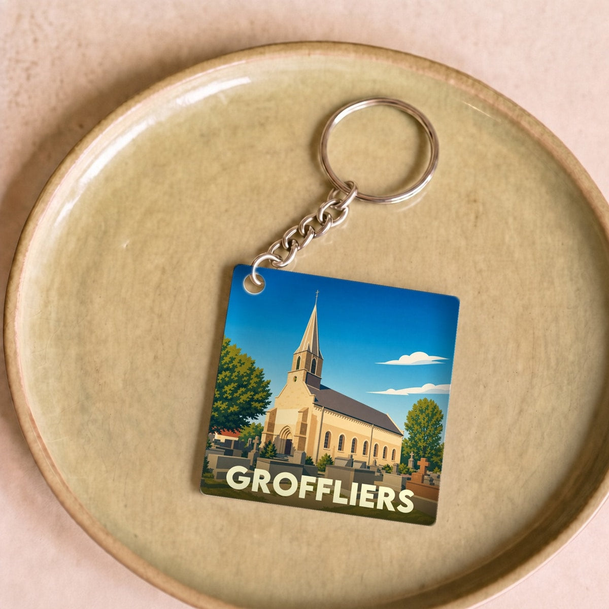 Porte-clés souvenir de la ville de Groffliers avec une illustration stylisée de son église.