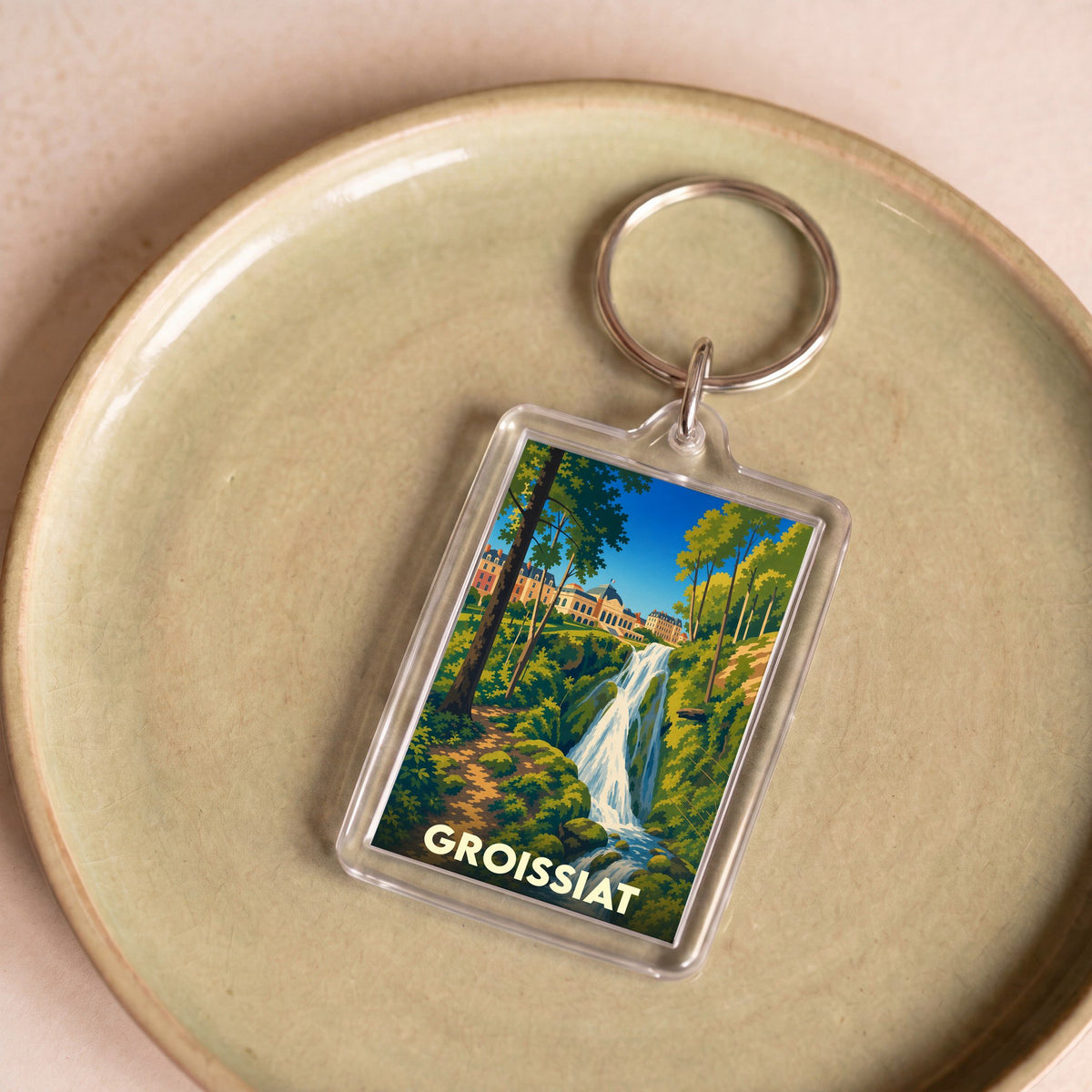 Porte-clés souvenir de la ville de Groissiat avec une illustration stylisée d'une cascade et de bâtiments.