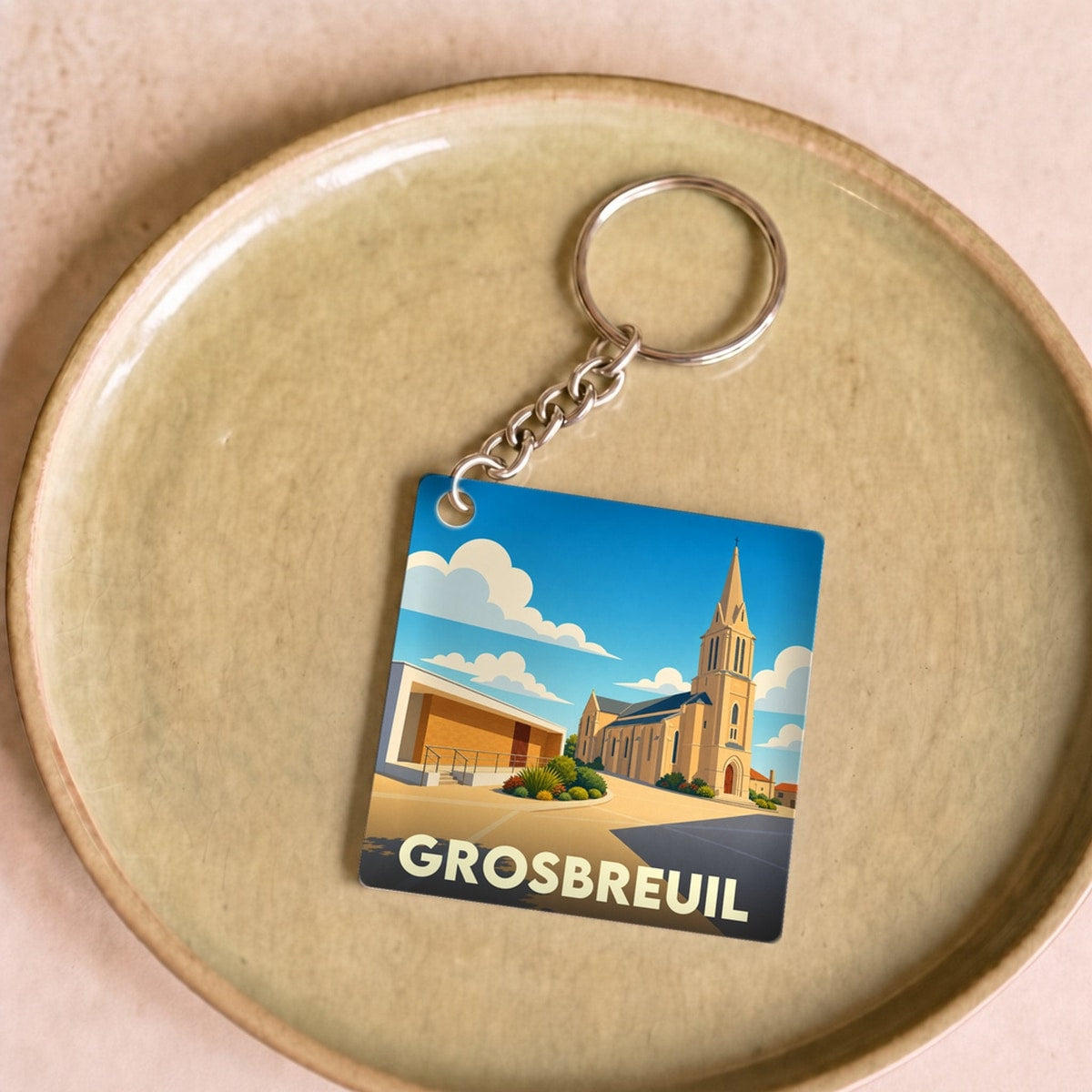 Porte-clés souvenir de la ville de Grosbreuil avec une illustration stylisée de son église.