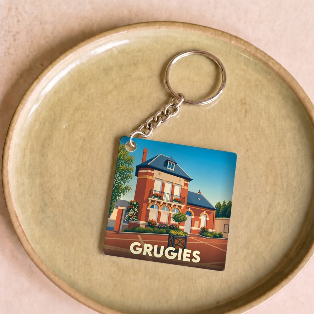 Porte-clés souvenir de la ville de Grugies avec une illustration stylisée de son hôtel de ville.