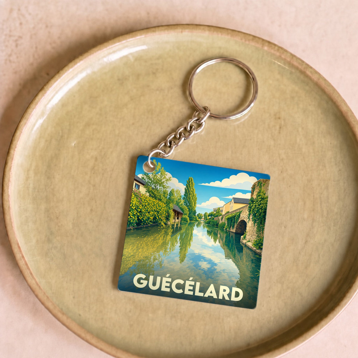 Porte-clés souvenir de la ville de Guécélard avec une illustration stylisée.