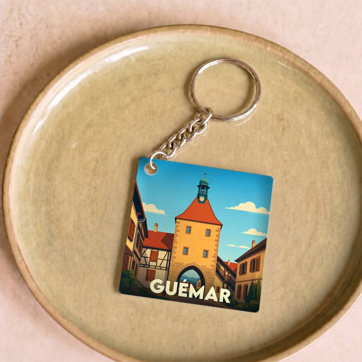 Porte-clés souvenir de la ville de Guémar avec une illustration stylisée.