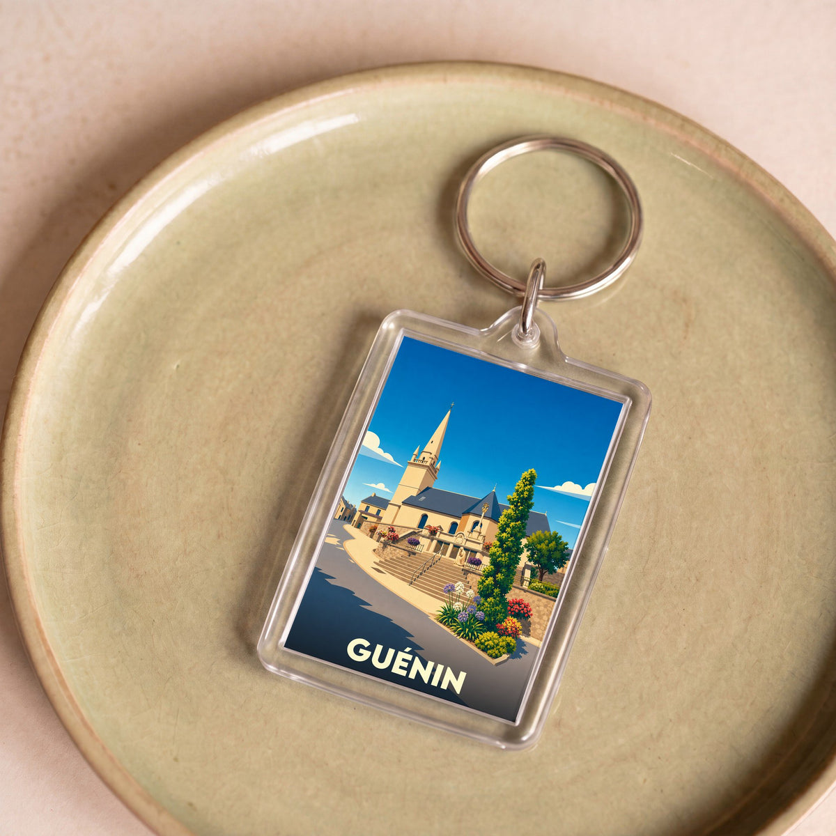 Porte-clés souvenir de la ville de Guénin avec une illustration stylisée de son église.