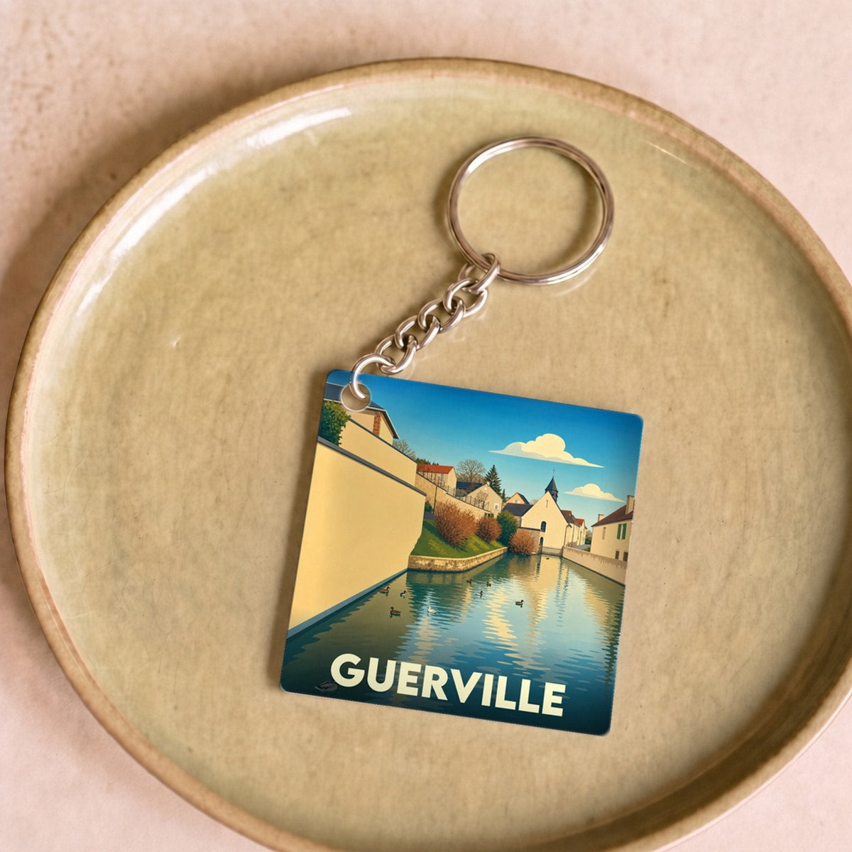 Porte-clés souvenir de la ville de Guerville avec une illustration stylisée d'un canal et de maisons.