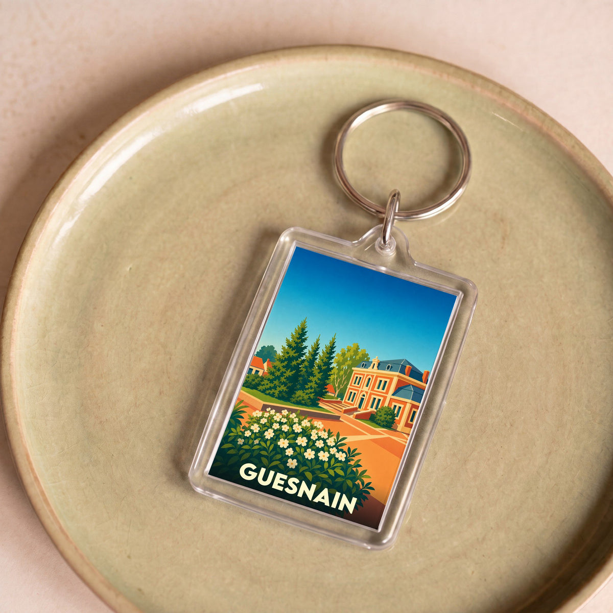 Porte-clés souvenir de la ville de Guesnain avec une illustration stylisée.