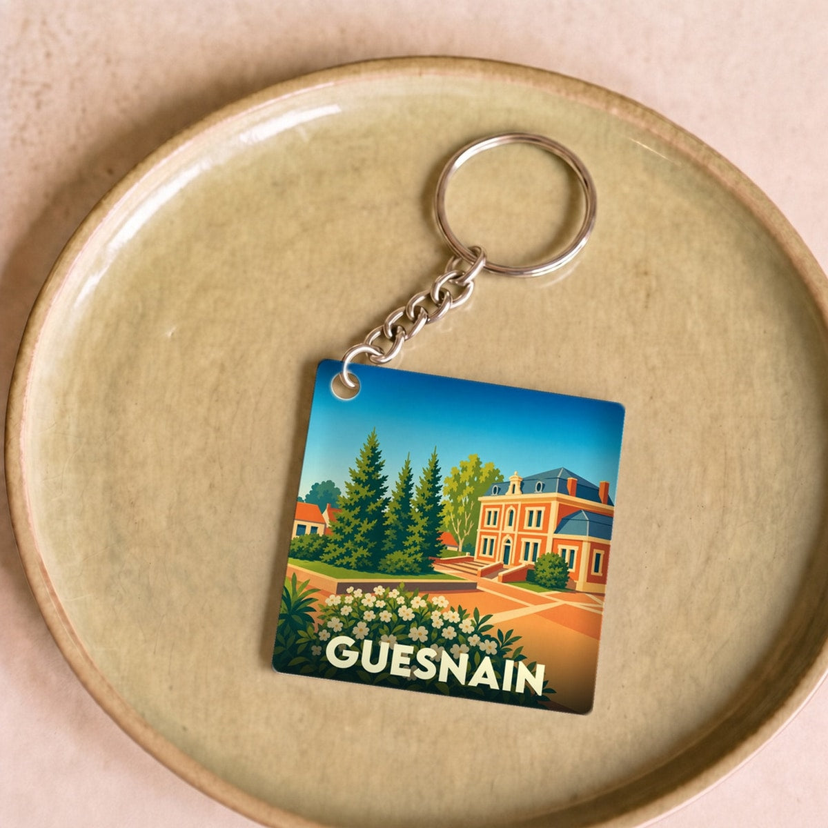 Porte-clés souvenir de la ville de Guesnain avec une illustration stylisée.