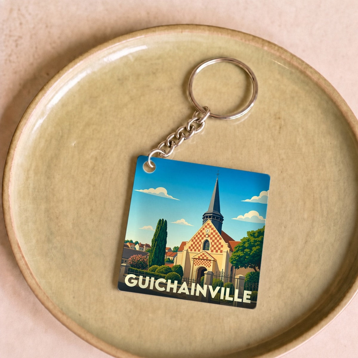 Porte-clés souvenir de la ville de Guichainville avec une illustration stylisée de son église.
