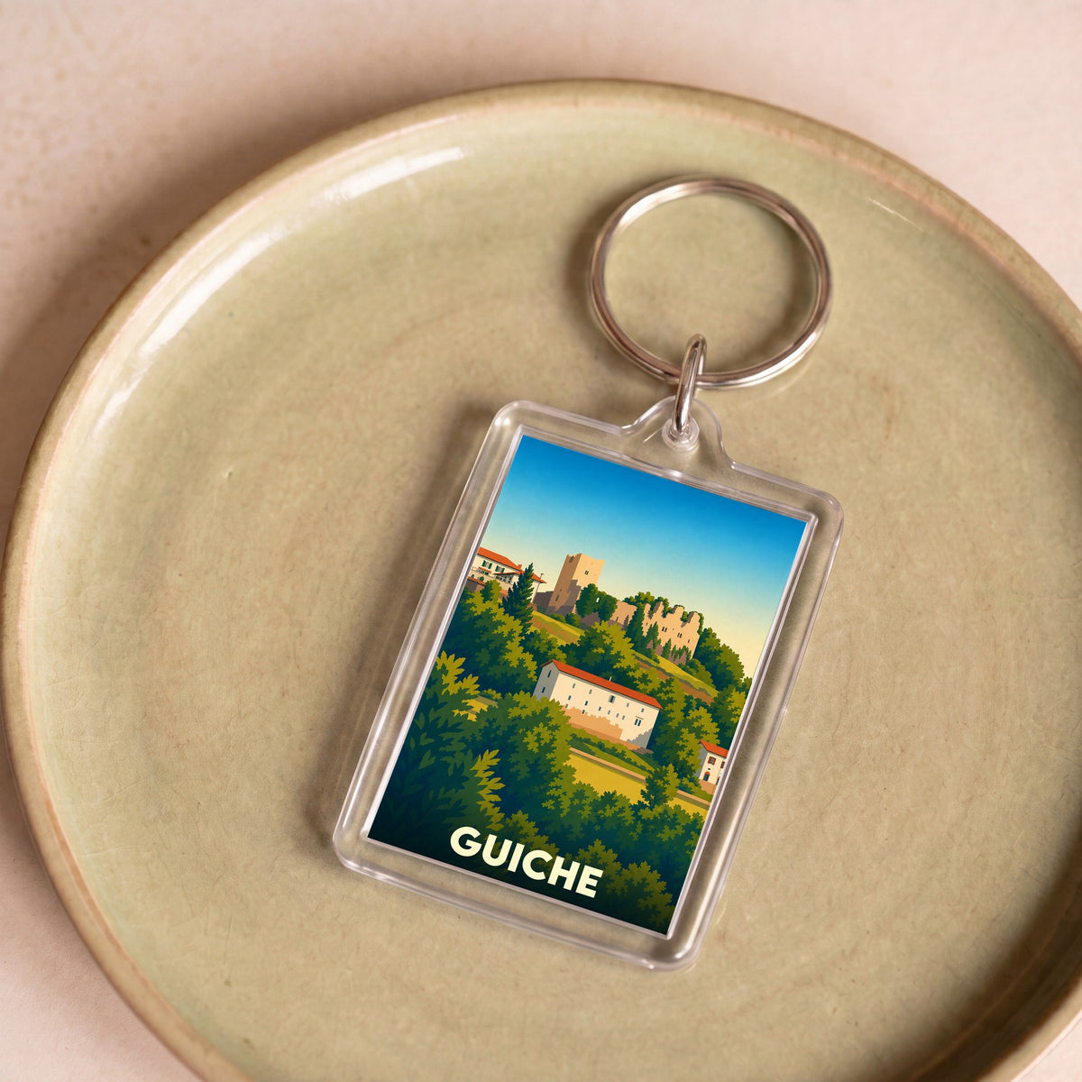 Porte-clés souvenir de la ville de Guiche avec une illustration stylisée.