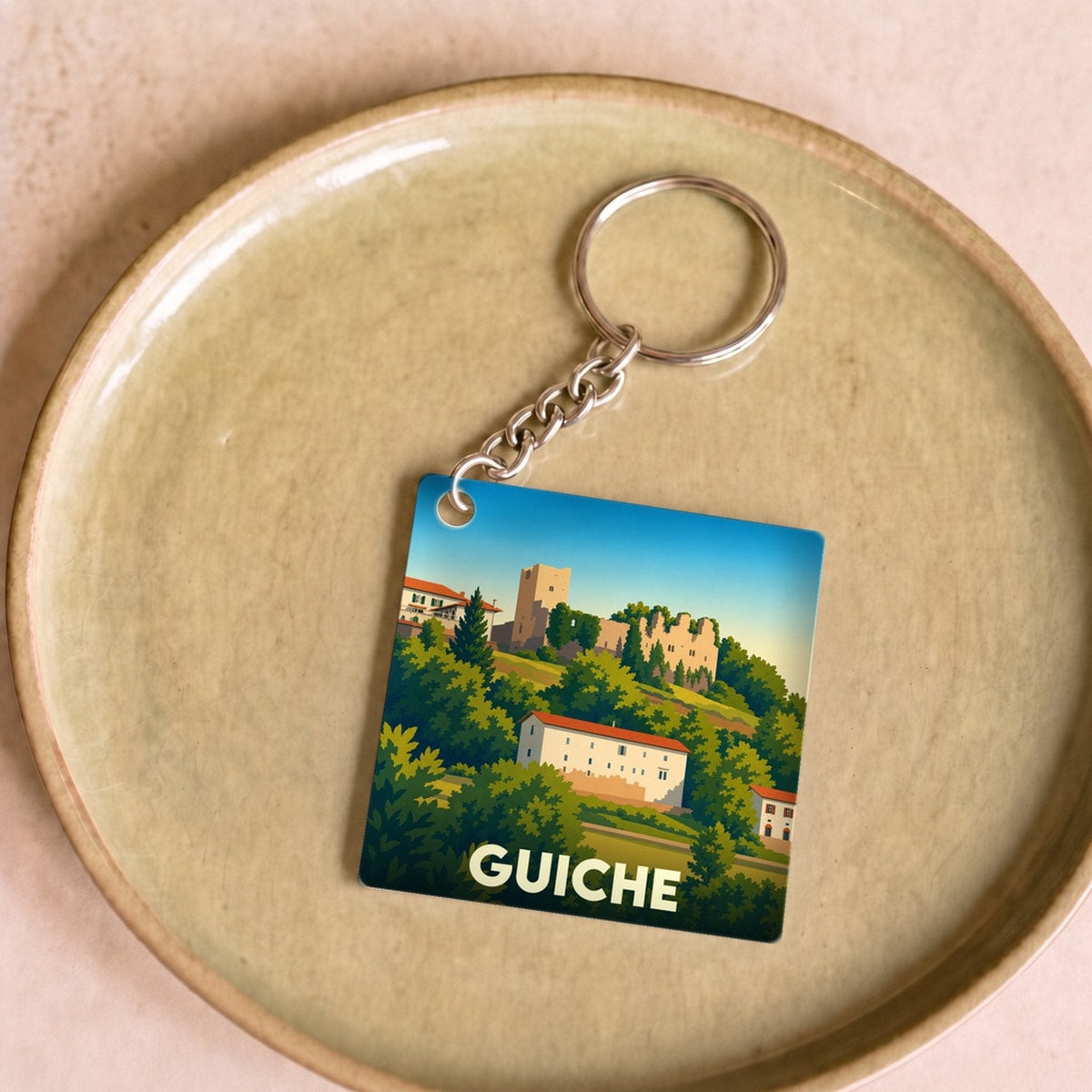 Porte-clés souvenir de la ville de Guiche avec une illustration stylisée.