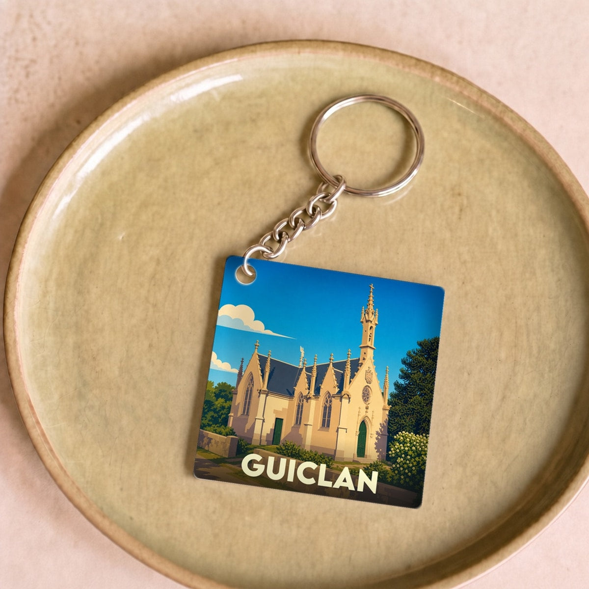 Porte-clés souvenir de la ville de Guiclan avec une illustration stylisée de son église.