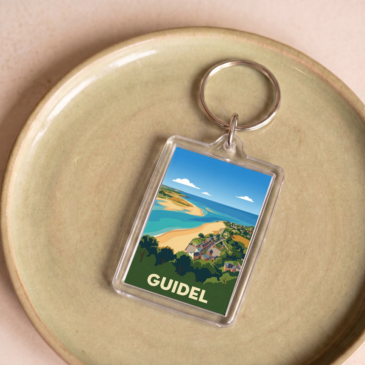 Porte-clés souvenir de la ville de Guidel avec une illustration stylisée de son littoral.
