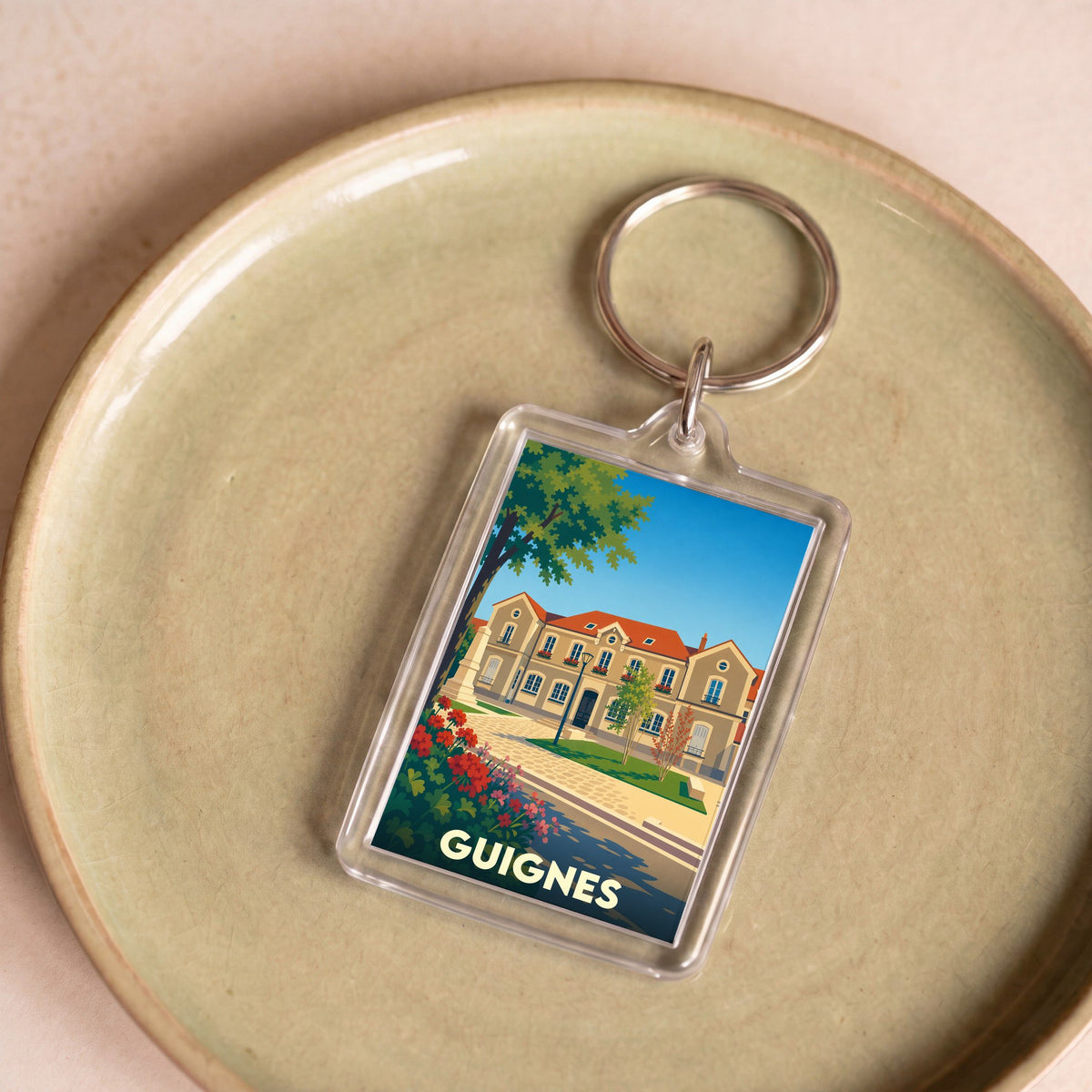 Porte-clés souvenir de la ville de Guignes avec une illustration stylisée.
