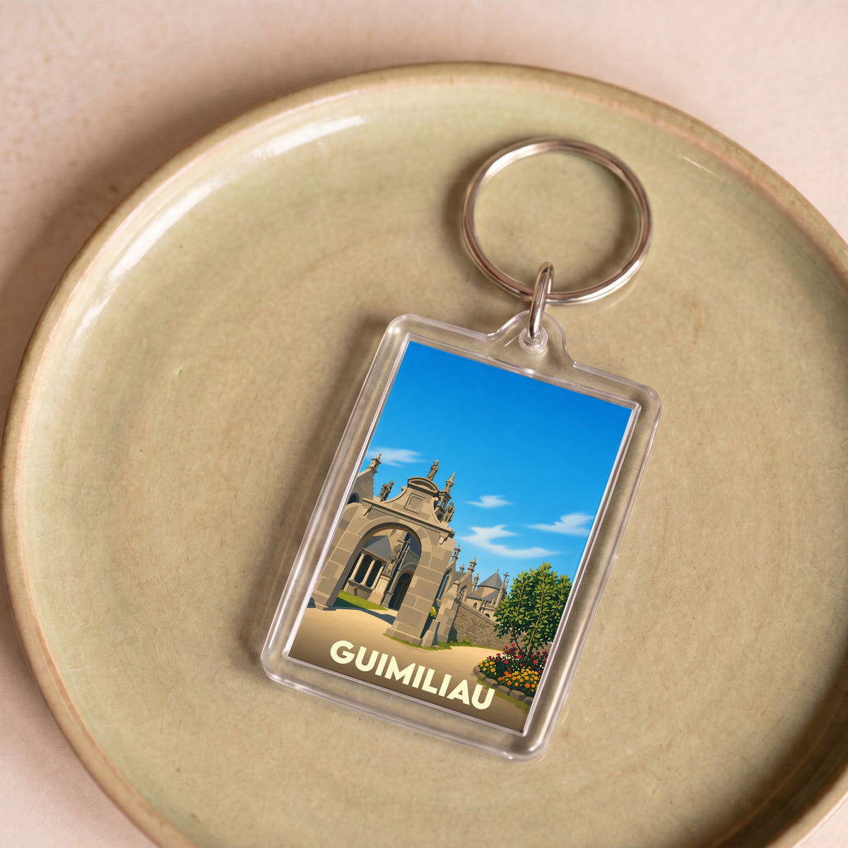 Porte-clés souvenir de la ville de Guimiliau avec une illustration stylisée.