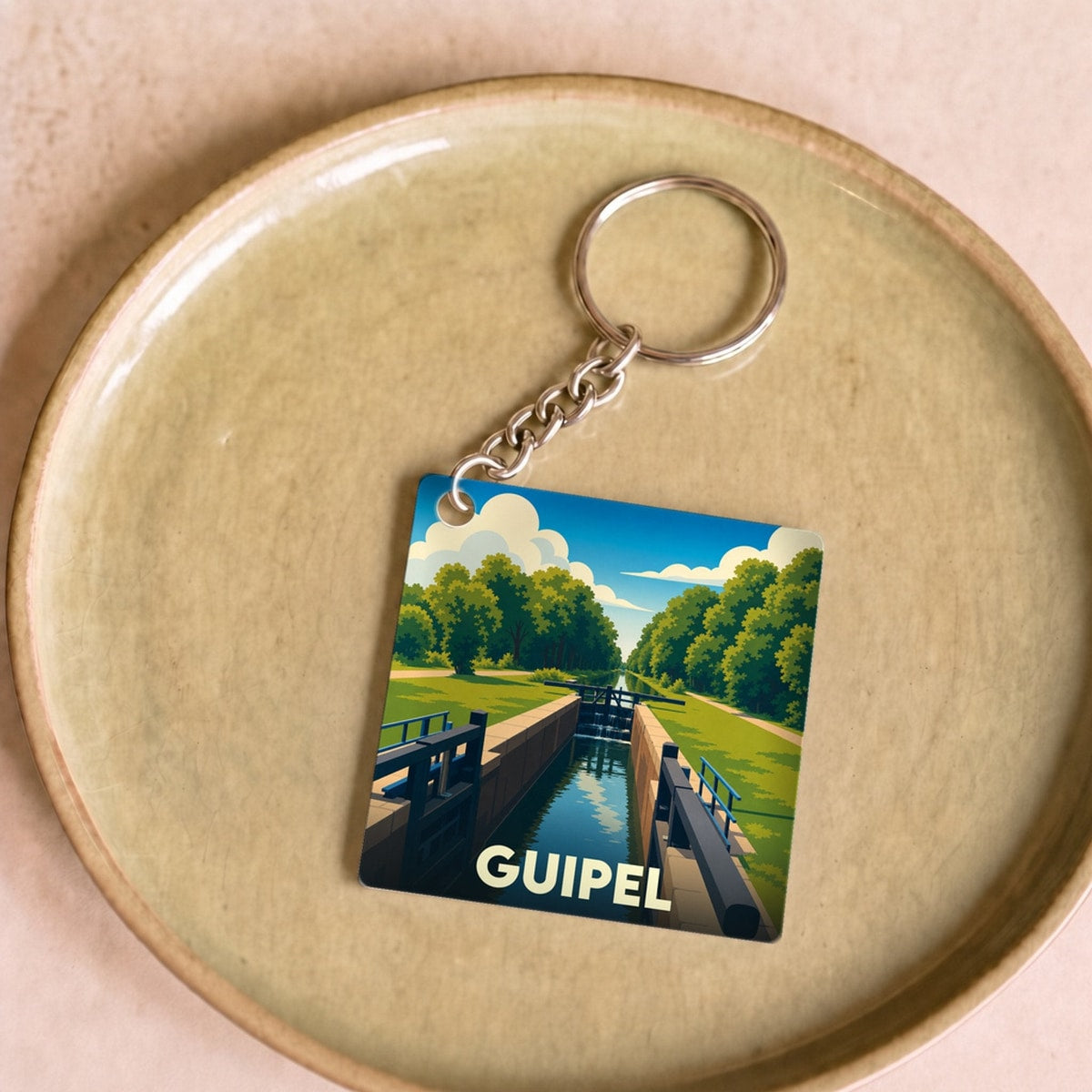 Porte-clés souvenir de la ville de Guipel avec une illustration stylisée d'une écluse sur le canal.