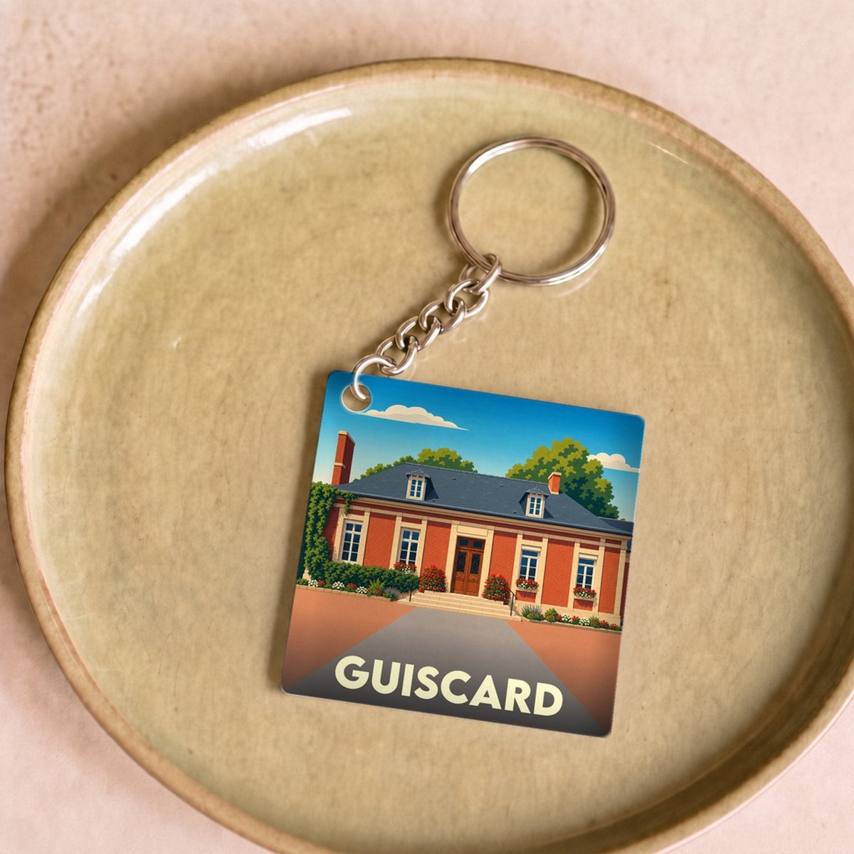 Porte-clés souvenir de la ville de Guiscard avec une illustration stylisée.