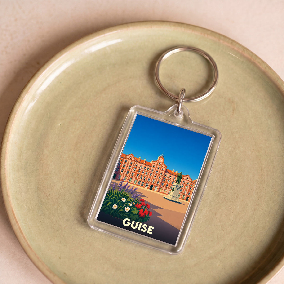 Porte-clés souvenir de la ville de Guise avec une illustration stylisée.