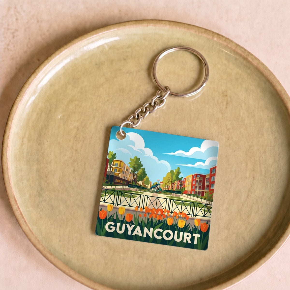 Porte-clés souvenir de la ville de Guyancourt avec une illustration stylisée.