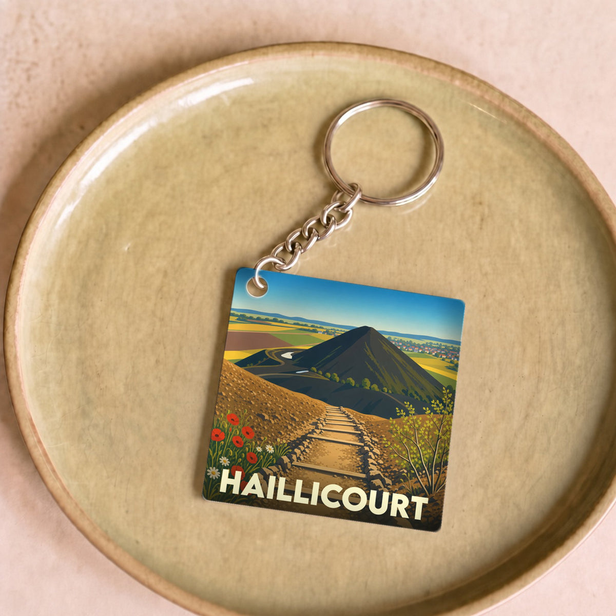 Porte-clés souvenir de la ville de Haillicourt avec une illustration stylisée de ses terrils.