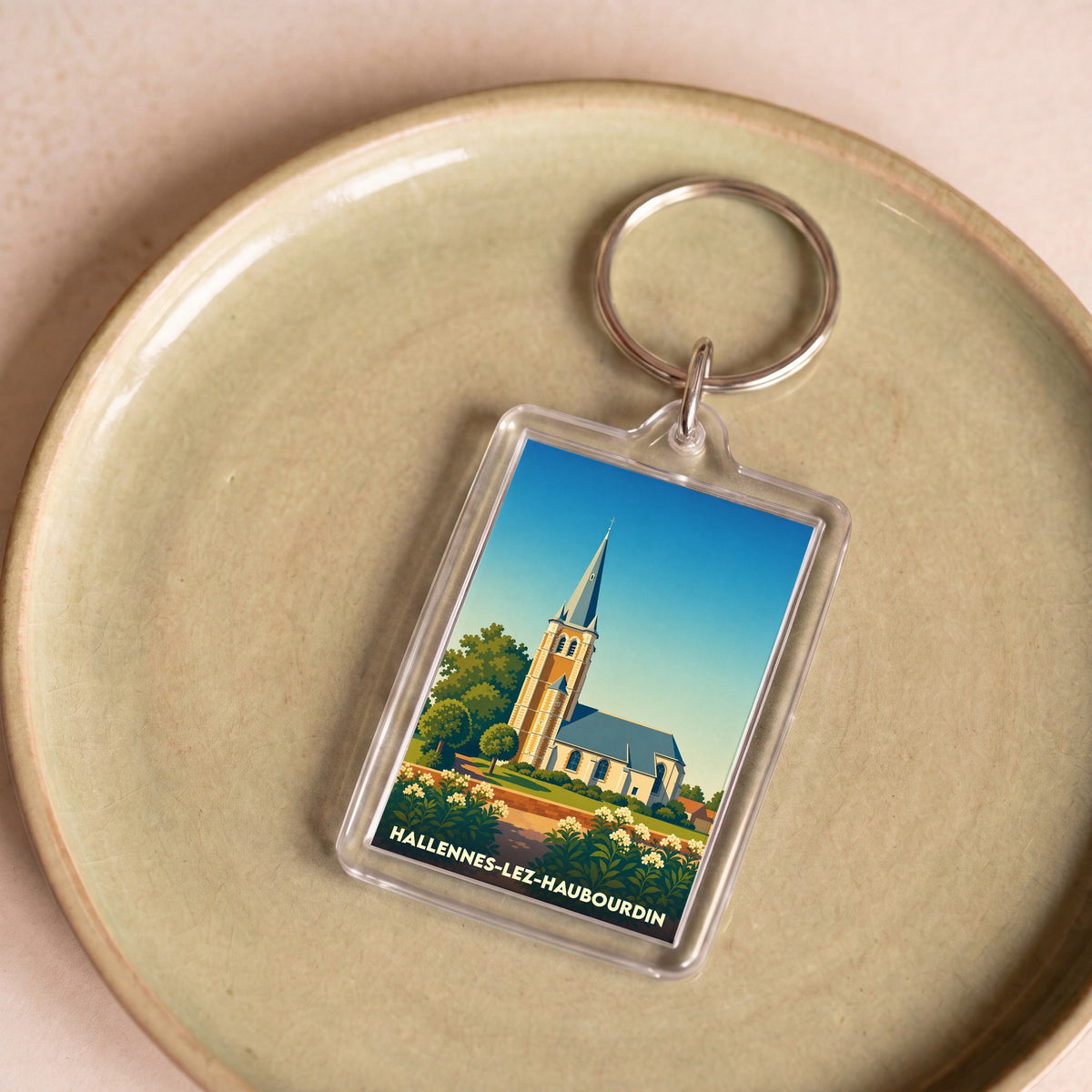 Porte-clés souvenir de la ville de Hallennes-lez-Haubourdin avec une illustration stylisée de son église.