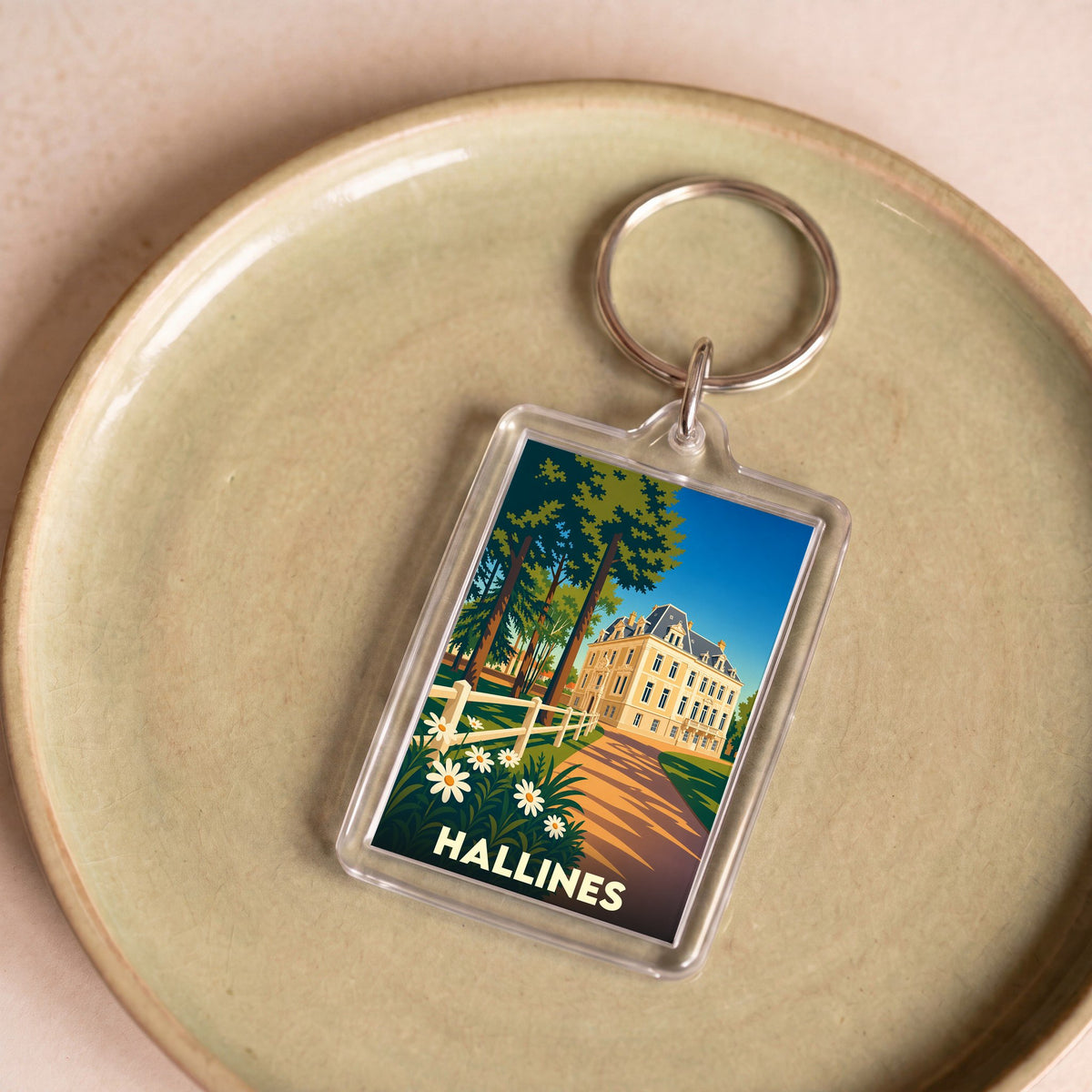 Porte-clés souvenir de la ville de Hallines avec une illustration stylisée d'un manoir.