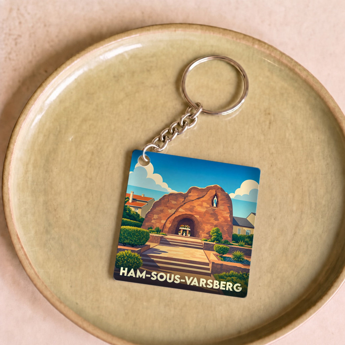 Porte-clés souvenir de la ville de Ham-sous-Varsberg avec une illustration stylisée d'une grotte sous un ciel bleu.