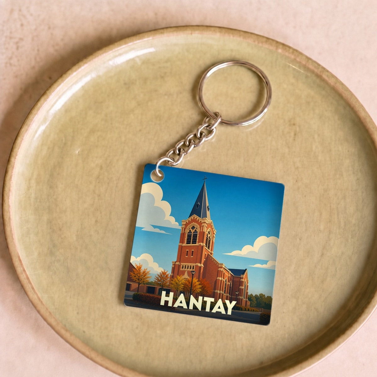 Porte-clés souvenir de la ville de Hantay avec une illustration stylisée de son église.