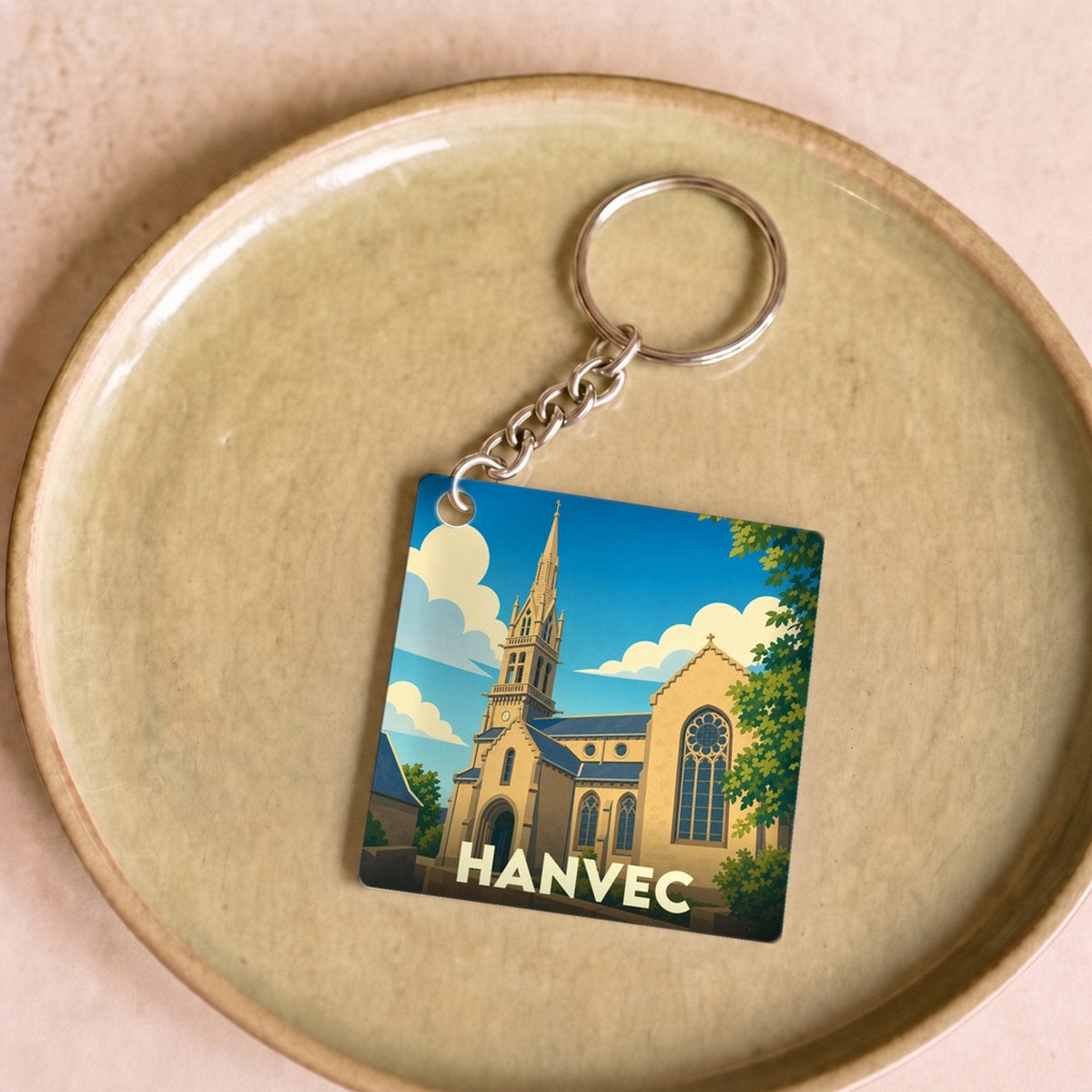 Porte-clés souvenir de la ville de Hanvec avec une illustration stylisée de son église.