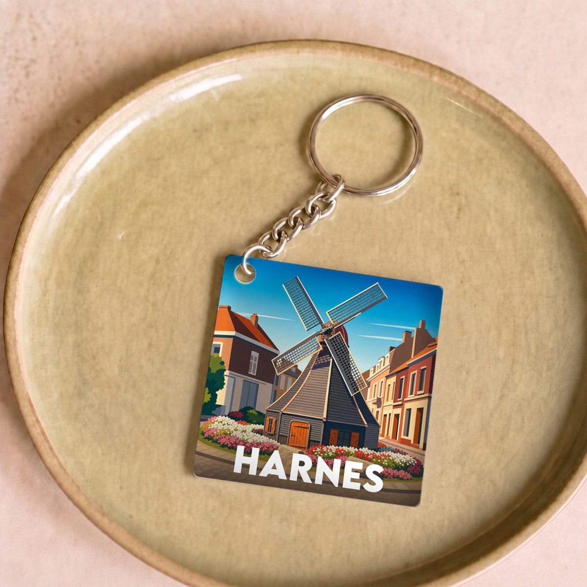 Porte-clés souvenir de la ville de Harnes avec une illustration stylisée.