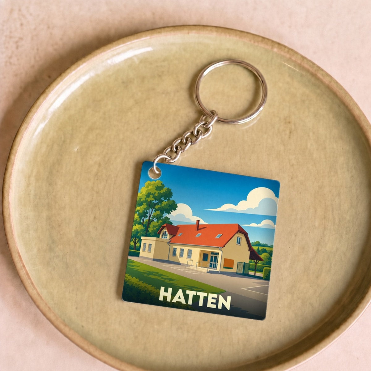 Porte-clés souvenir de la ville de Hatten avec une illustration stylisée.