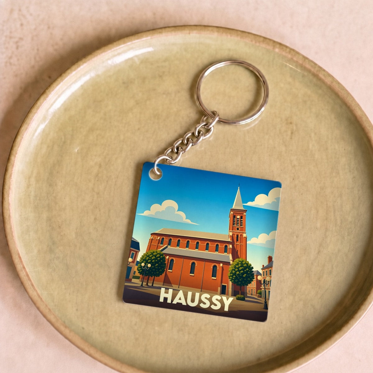 Porte-clés souvenir de la ville de Haussy avec une illustration stylisée d'une église en briques.