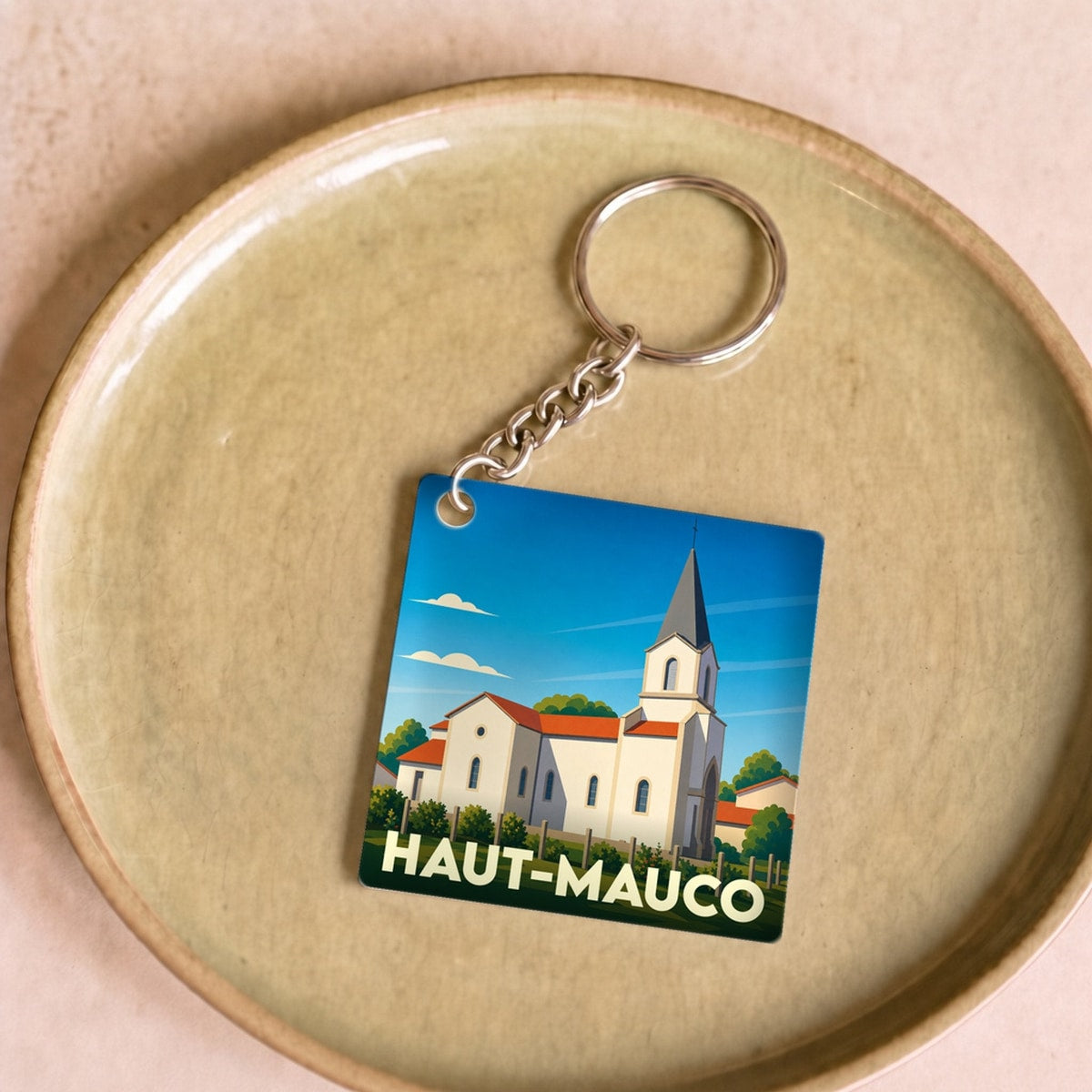 Porte-clés souvenir de la ville de Haut-Mauco avec une illustration stylisée de son église.