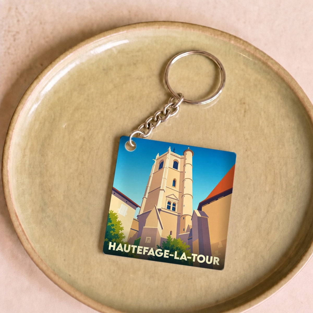Porte-clés souvenir de la ville de Hautefage-la-Tour avec une illustration stylisée de sa tour historique.