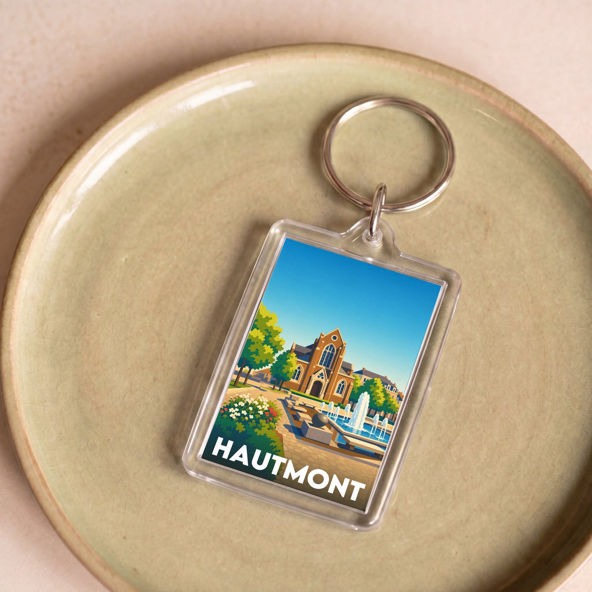 Porte-clés souvenir de la ville de Hautmont avec une illustration stylisée.