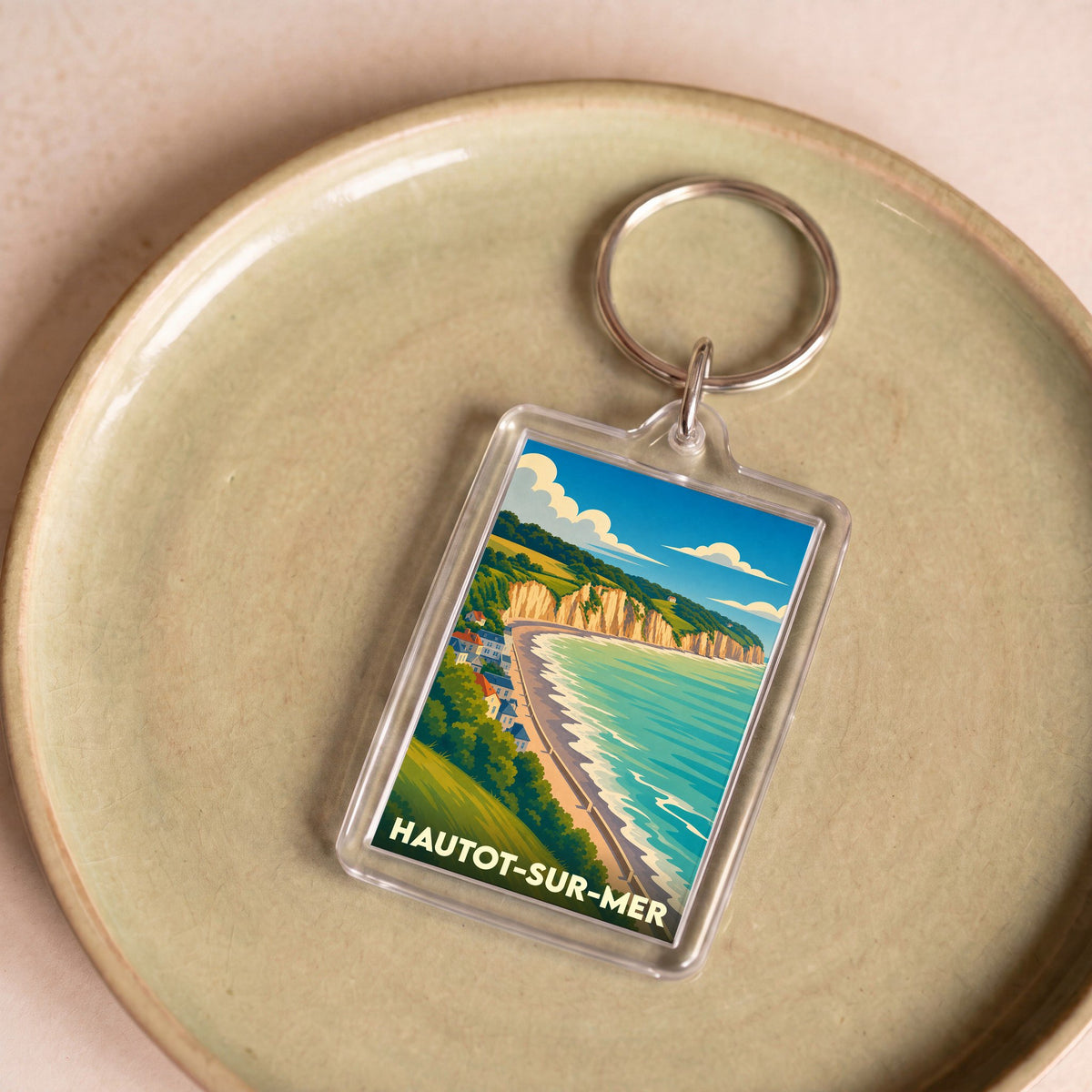 Porte-clés souvenir de la ville de Hautot-sur-Mer avec une illustration stylisée de ses falaises et de sa plage.