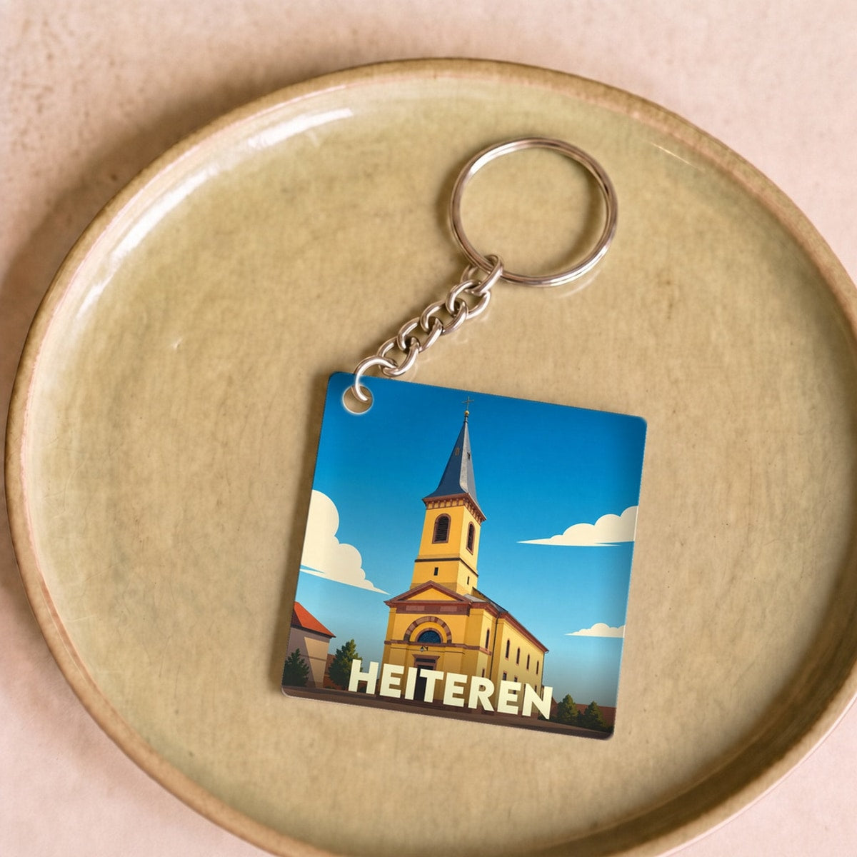 Porte-clés souvenir de la ville de Heiteren avec une illustration stylisée d'une église sous un ciel bleu.