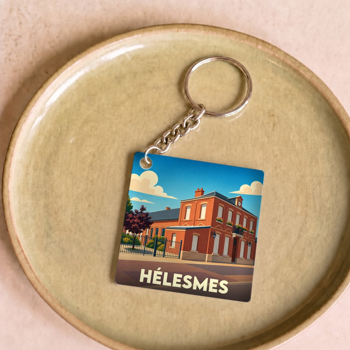 Porte-clés souvenir de la ville de Hélesmes avec une illustration stylisée de sa mairie.
