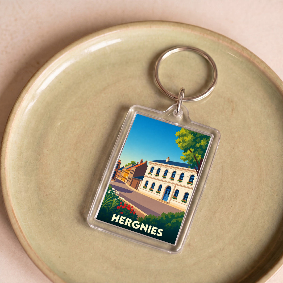Porte-clés souvenir de la ville de Hergnies avec une illustration stylisée.