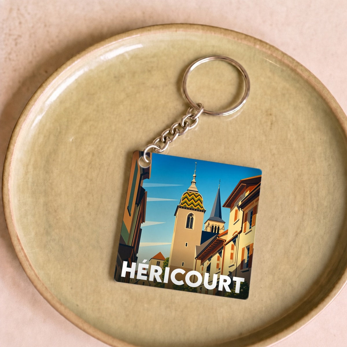 Porte-clés souvenir de la ville de Héricourt avec une illustration stylisée.