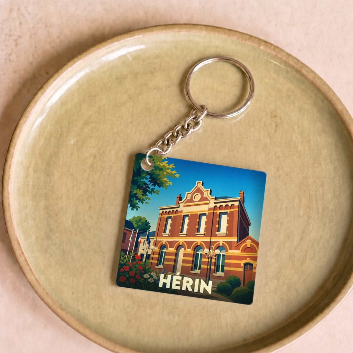 Porte-clés souvenir de la ville de Hérin avec une illustration stylisée de son hôtel de ville.