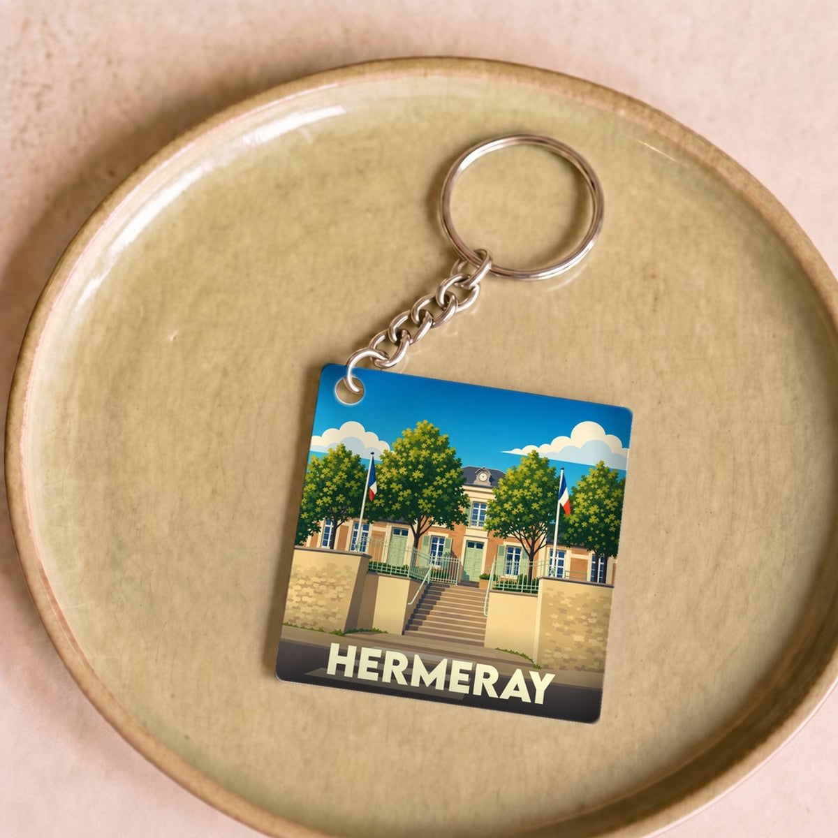Porte-clés souvenir de la ville de Hermeray avec une illustration stylisée de la mairie.
