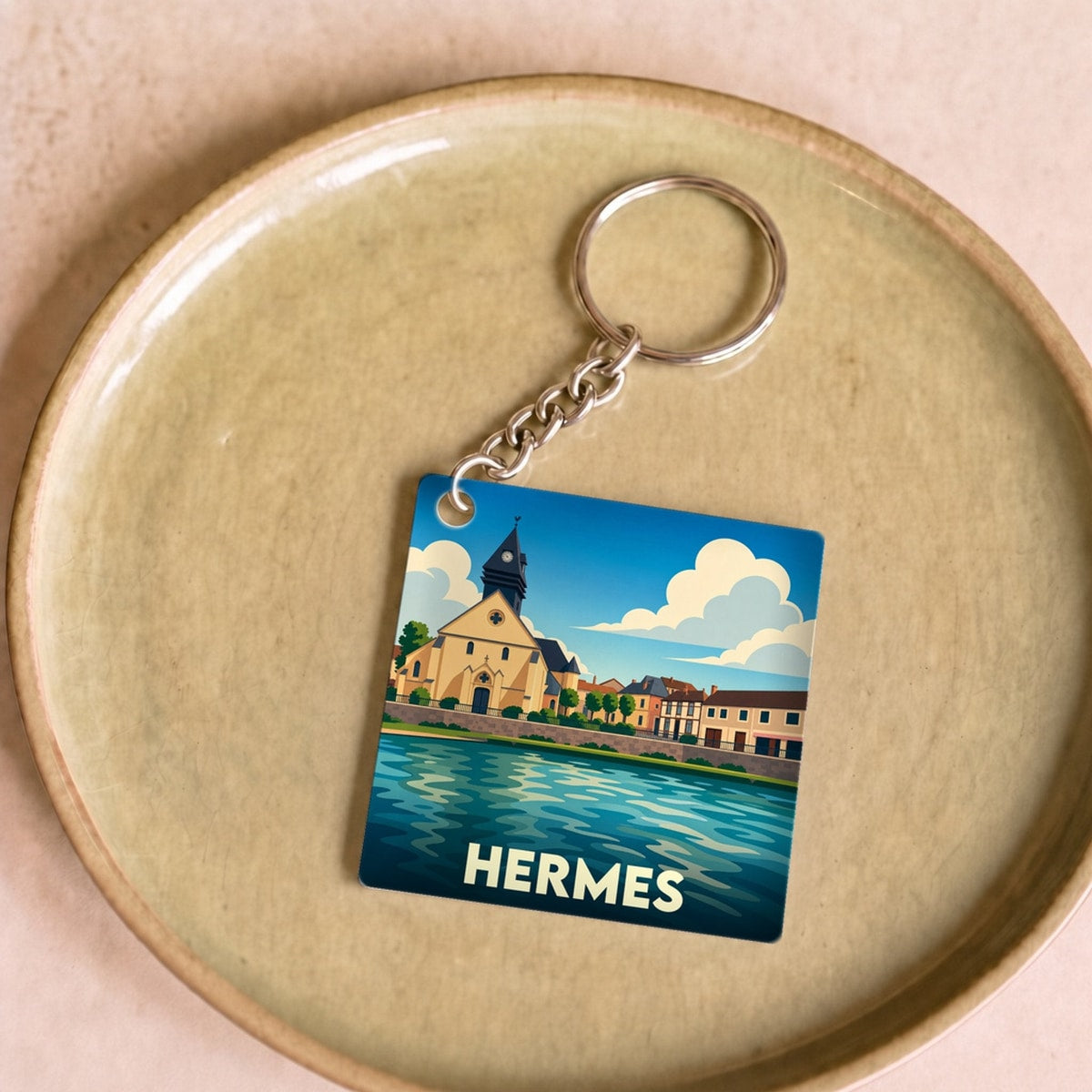 Porte-clés souvenir de la ville de Hermes avec une illustration stylisée d'un paysage urbain au bord de l'eau.