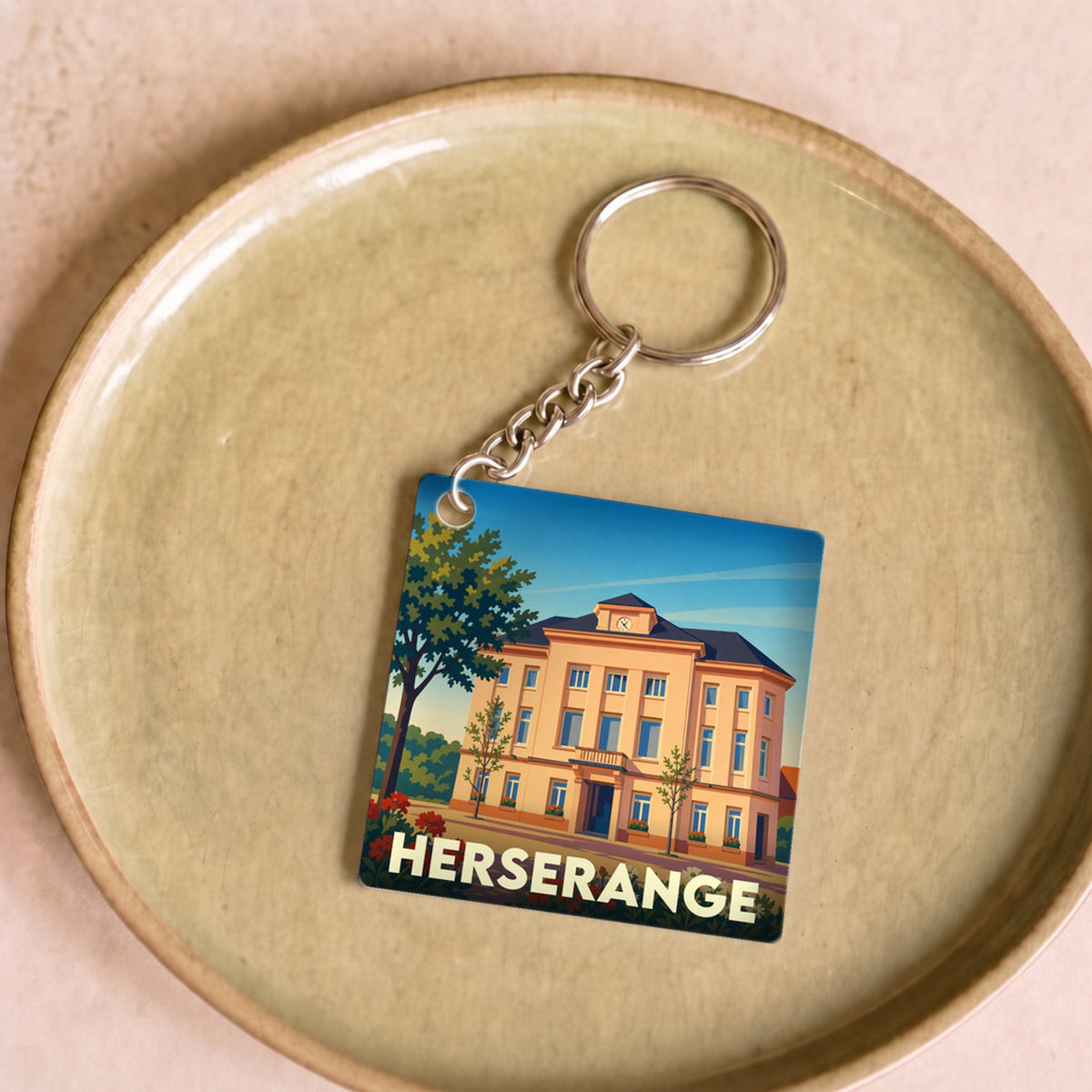 Porte-clés souvenir de la ville de Herserange avec une illustration stylisée de son hôtel de ville.