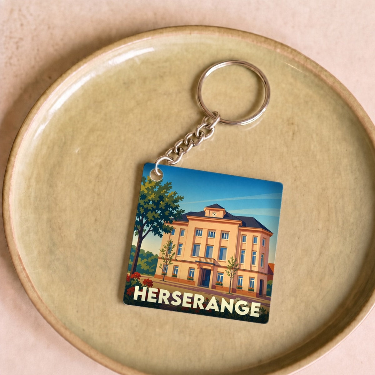 Porte-clés souvenir de la ville de Herserange avec une illustration stylisée de son hôtel de ville.